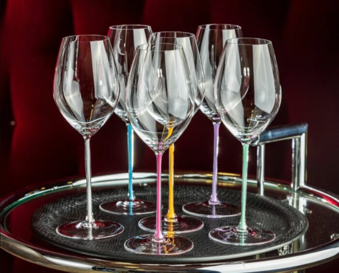 Champagneglass på et brett. Glassene har ulik farge på stilken. Oransje, rosa, mint, blå og lavendel